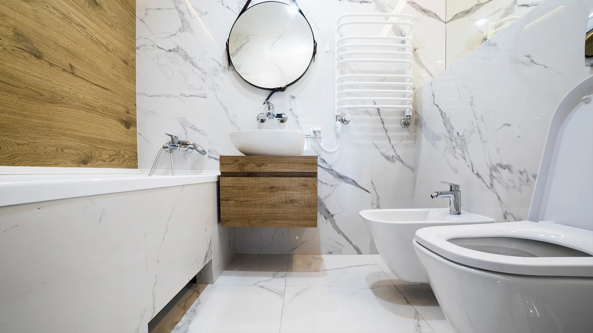 Luxe badkamer met marmerlook tegels, ligbad, zwevend meubel en designradiator