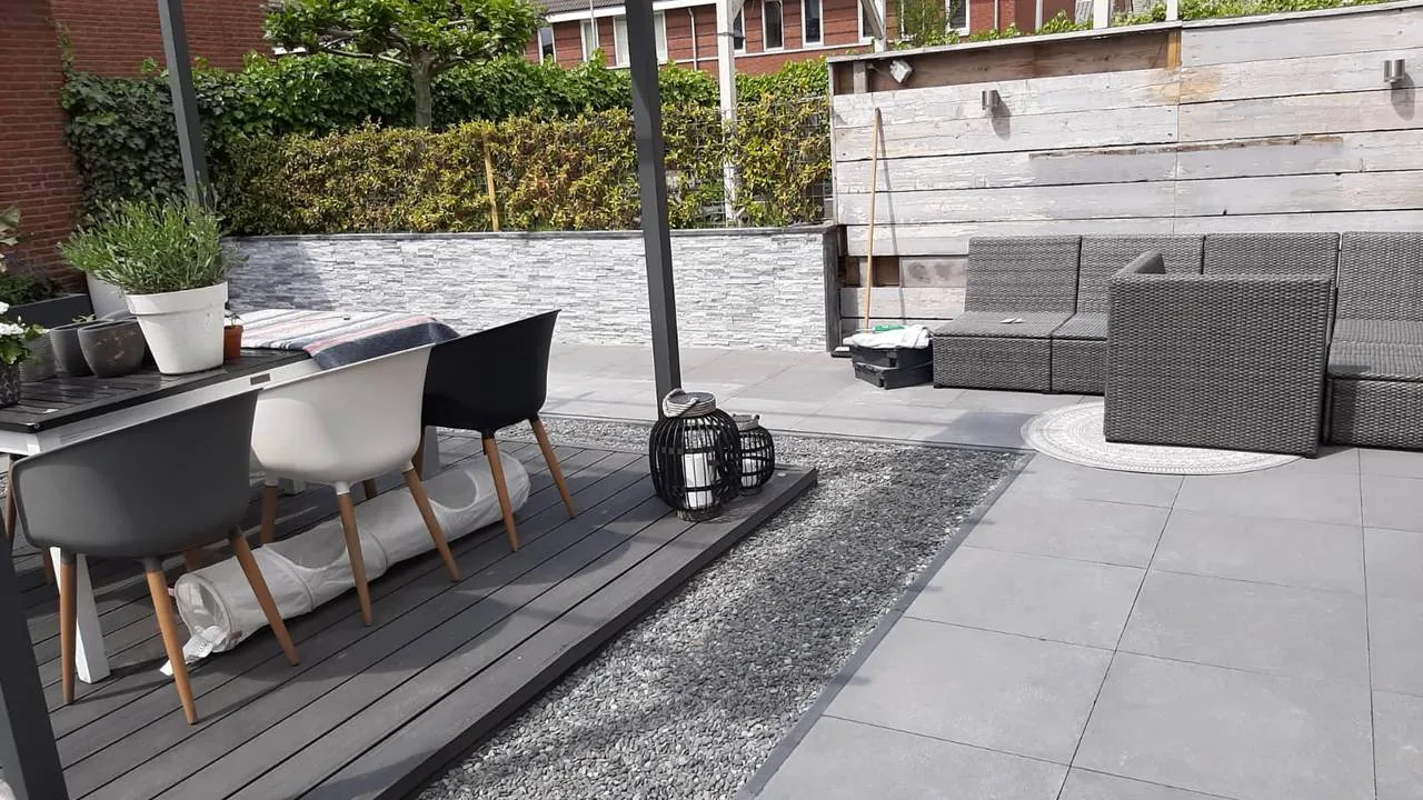 Moderne tuin met composiet vlonderterras, betontegels, grindstrook en loungehoek