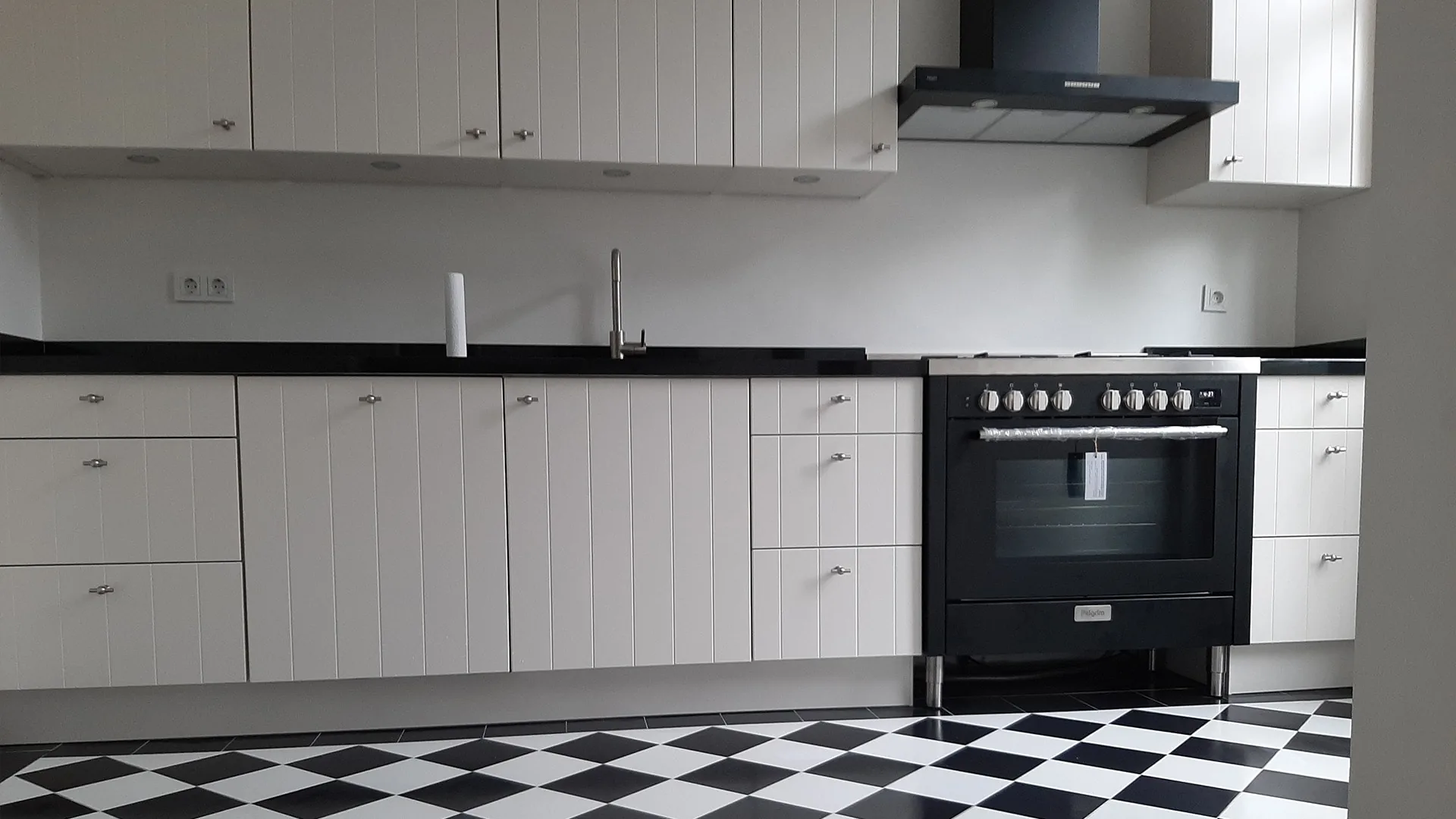Landelijke keuken in zwart-wit met granieten werkblad, fornuis en geblokte tegelvloer